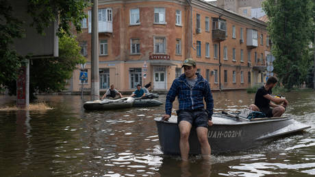 Volunteers carry local residents on boats during an evacuation from a flooded area in Kherson on June 8, 2023, following damages sustained at Kakhovka hydroelectric power plant dam.