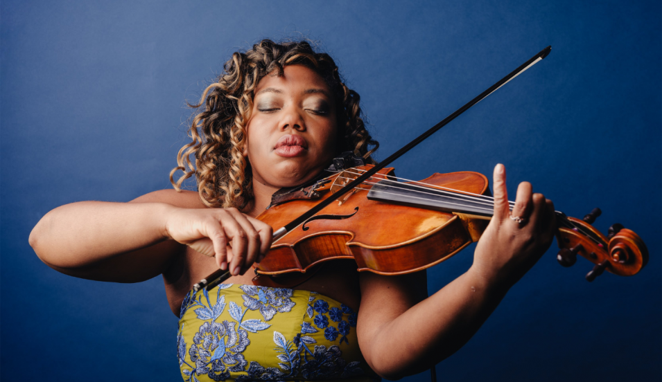 Kathryn Patricia Cobbler playing viola in front of a blue background. 