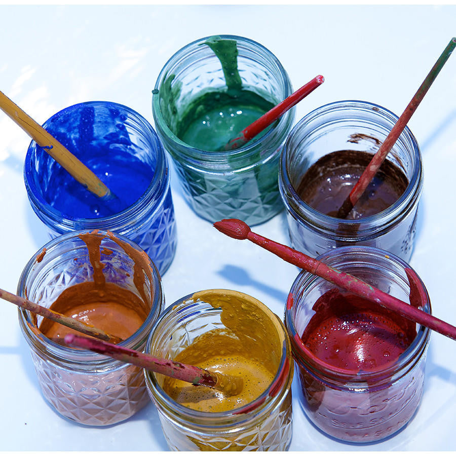 Six open jars of Natural Earth Paint with paint brushes, arranged in a circle