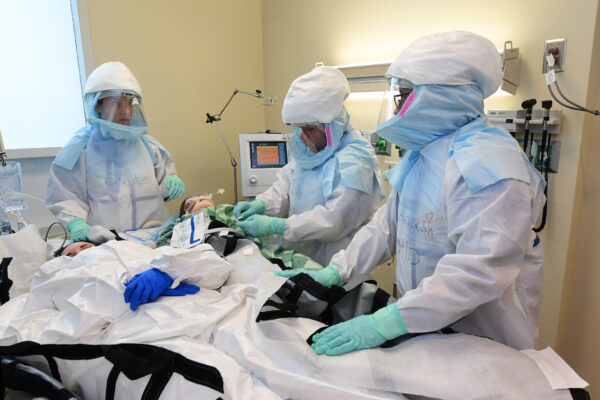 Health care workers in full protective equipment conduct drill in patient setting