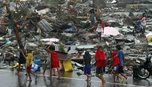 Survivors walking past debris of flattened homes 