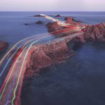 brand image - Long exposure of rainbow-colored light traces on rock bridge over ocean.