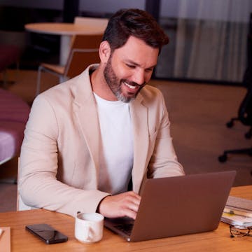 Homem sorridente mexendo no notebook