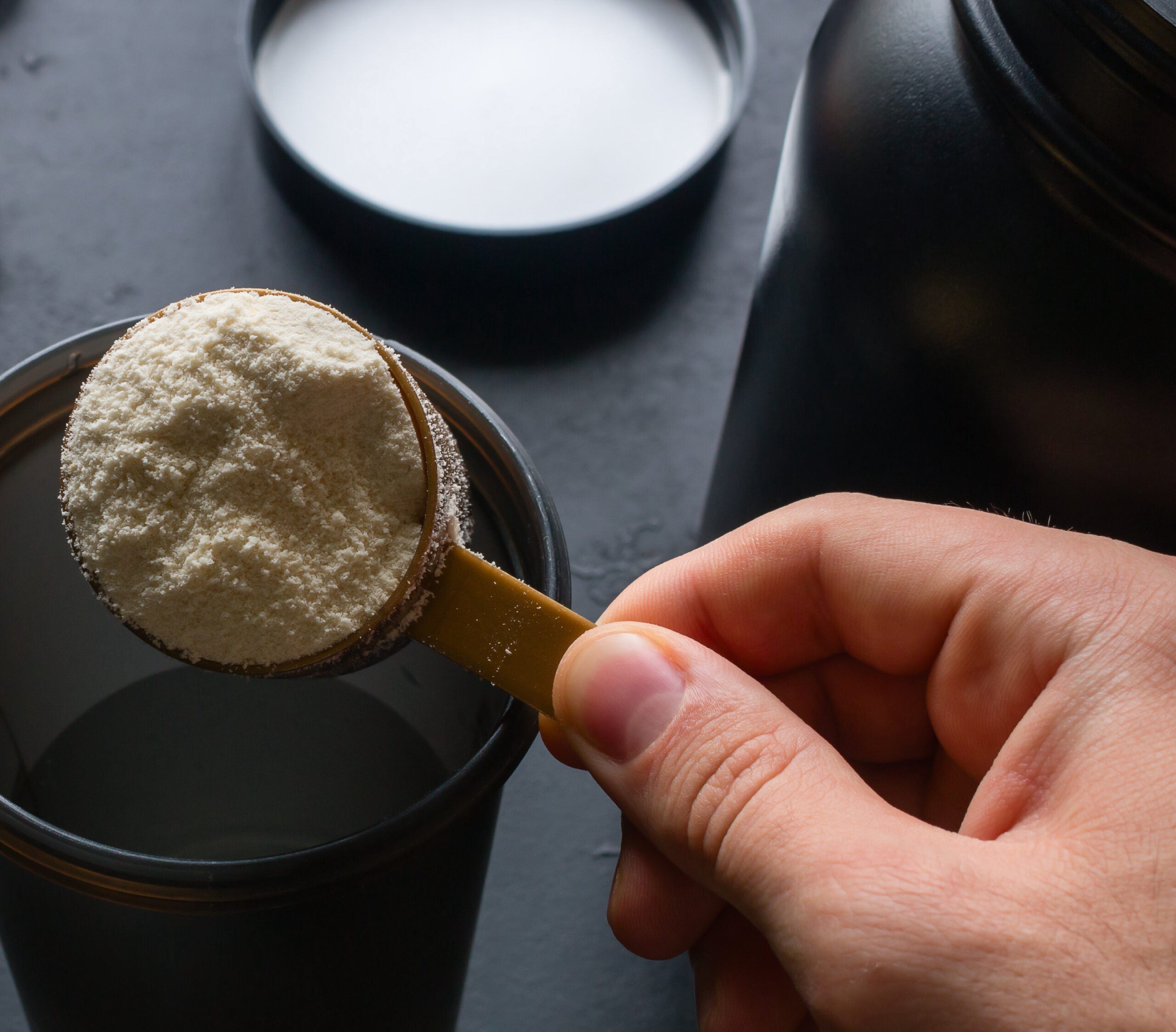 person making a workout shake including protein powder