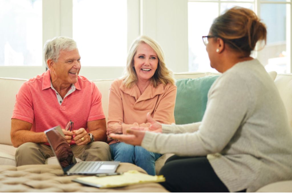 Two people sitting in a living room with another woman.