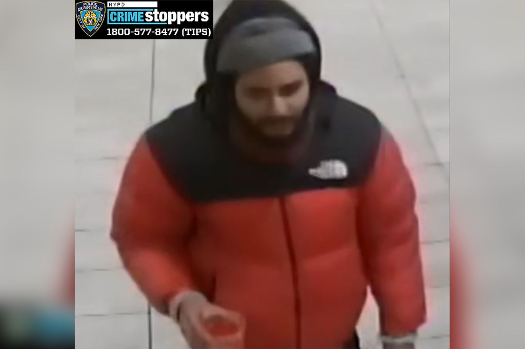 Roberto Ortiz wearing a red and black winter coat, gray hat, black pants, and pushing a rolling duffle bag.