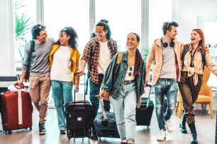 A group of friends happily walk through an airport.