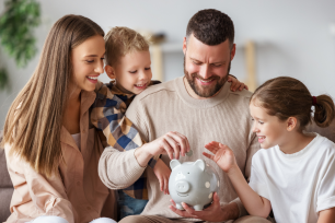 A family eagerly inserts coins into a piggy bank.