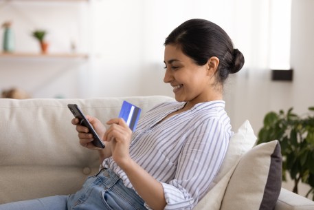 A woman uses her phone and credit card to shop online.