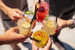 Five hands raising exotic cocktails on ice in a celebratory toast