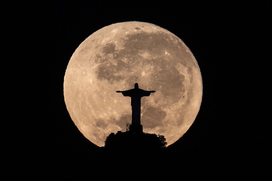 Moon sets behind the Christ the Redeemer monument in Rio de Janeiro, Brazil.