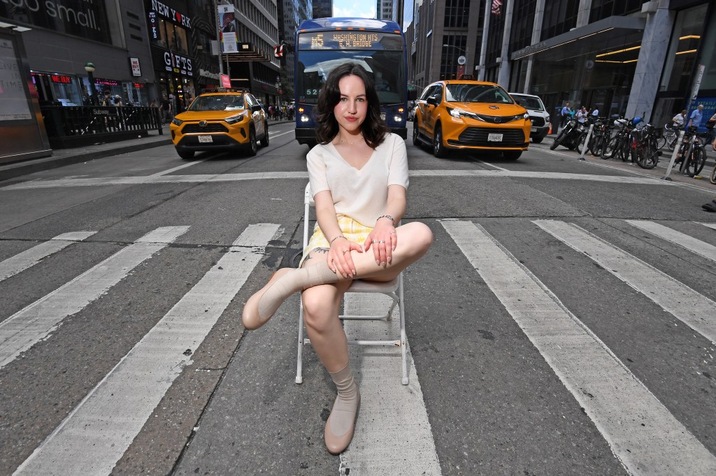 NY Post reporter Brooke Kato trying on 'Borg' sock shoes by Tibi while sitting on a chair in a street, photo by Matthew McDermott