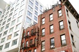 Modern high rise apartment building under construction adjacent to old-fashioned buildings on W38th Street, New York, NY