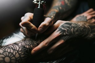 Tattoo artist with tattooed hands at work