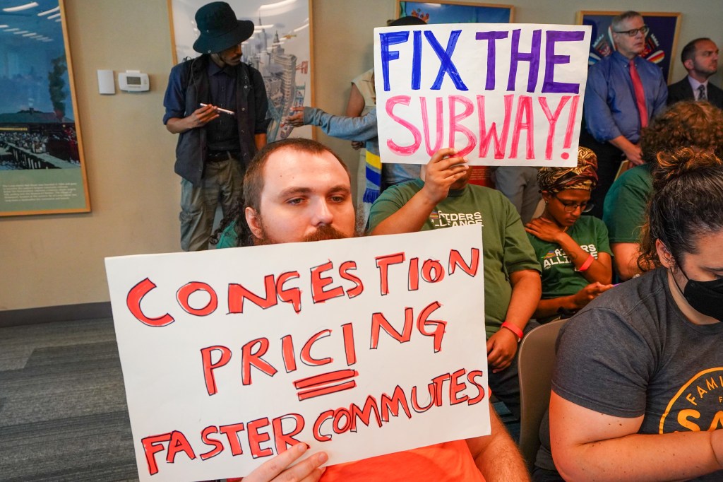 Supporters of congestion pricing hold signs at an MTA board meeting in support of tolls.