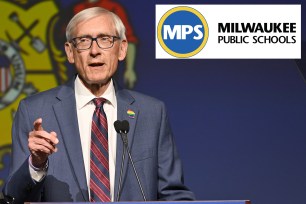 Tony Evers in a suit and tie speaking into a microphone at the WisDems 2024 State Convention in Milwaukee, Wisconsin