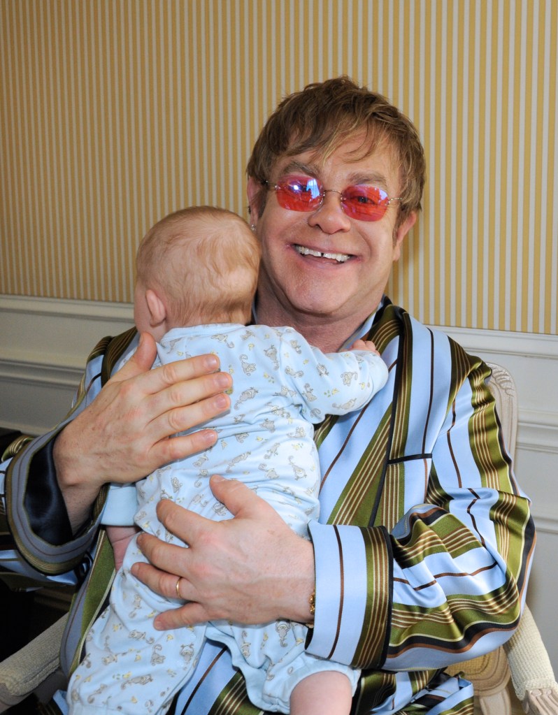 Elton John holding a baby. 