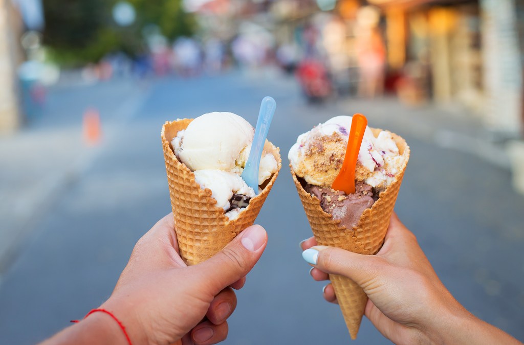 Beautiful bright ice cream with different flavors in the hands of a couple.