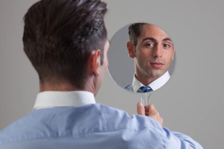 Businessman looking himselft in a mirror