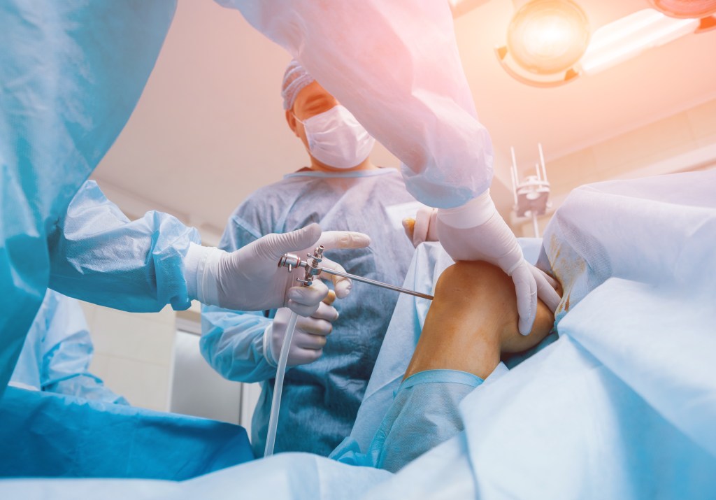 Orthopedic surgeons performing arthroscope knee surgery in a modern operating room