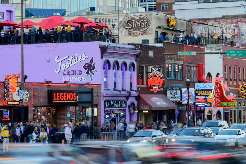 Tourists survey the bars and country music venues in the Lower Broadway entertainment district in Nashville, Tennessee. 