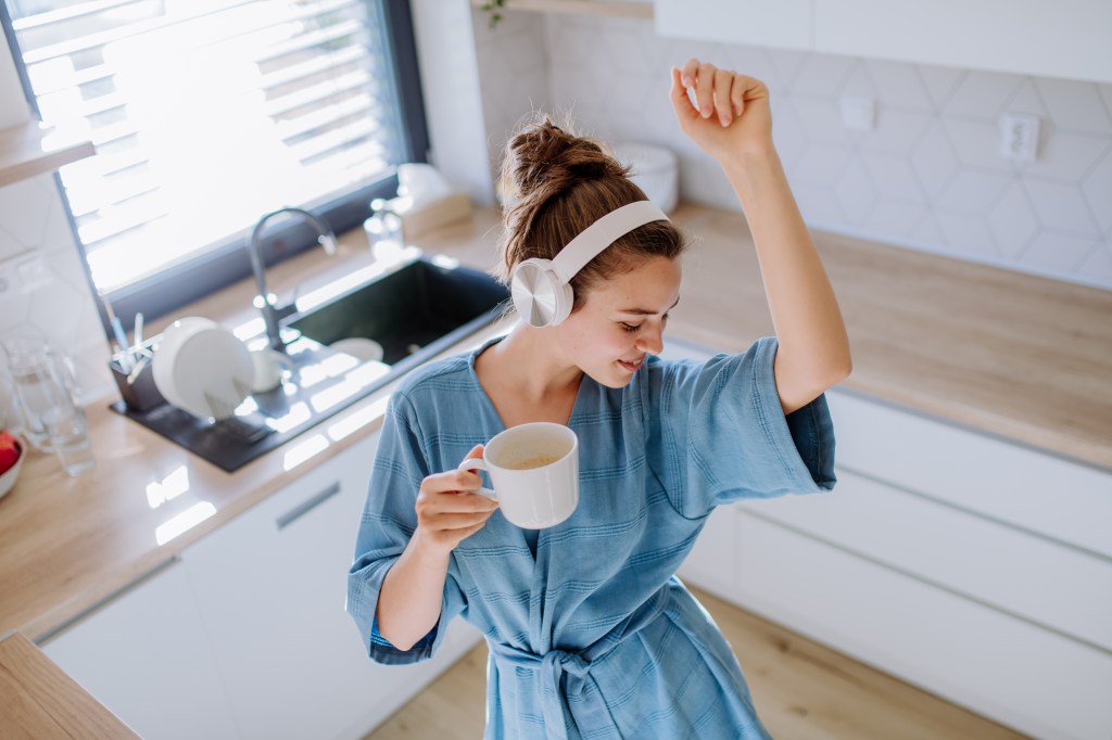 Young woman enjoying cup of coffee and listening music alone