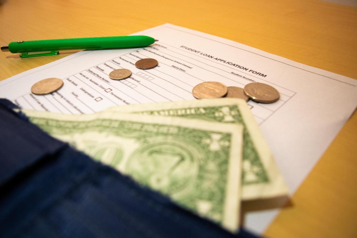 A document with a green pen, two one dollar bills and six coins on top of it.