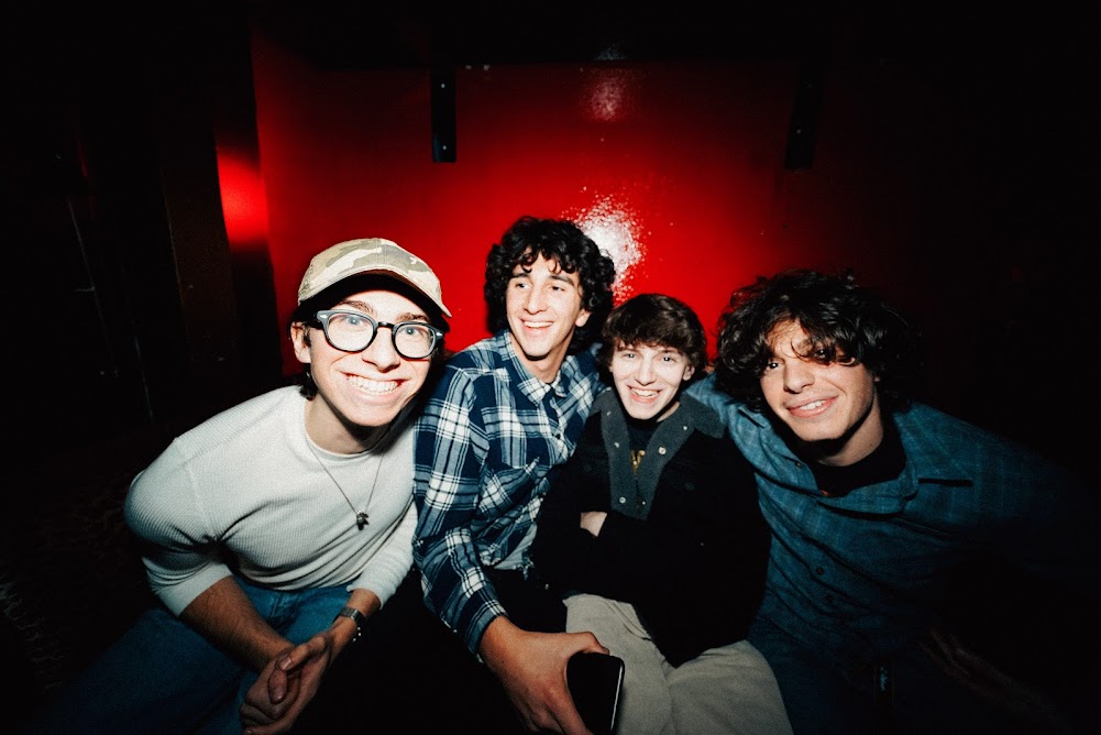 A group of four people smiling at a camera in a red room.