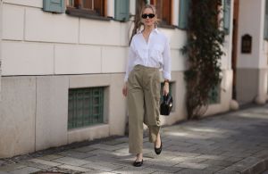 MUNICH, GERMANY - MARCH 22: Marlies Pia Pfeifhofer seen wearing Versace black sunglasses, gold earrings and necklace, LaMarel white cotton buttoned blouse shirt, Agolde beige long pants, Jimmy Choo black leather / gold bag and Chanel black leather ballerinas, on March 22, 2024 in Munich, Germany. (Photo by Jeremy Moeller/Getty Images)