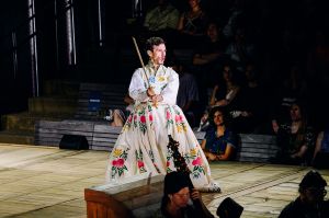 A man in a dress performs on a stage