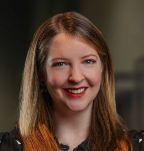 A photo of a smiling woman with blond hair that has distinctive orange tips