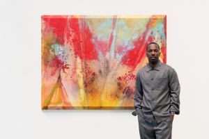 A man stands in front of a colorful abstract painting