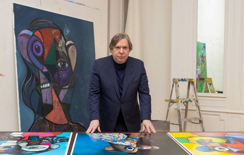 Image of a man in black suit with some colorful prints of Picasso-like figures.