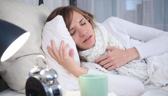 Junge Frau liegt krank im Bett