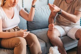 Young heterosexual couple are quarreling while sitting on couch at home.