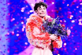 Switzerland's flag is seen in the foreground as Swiss singer Nemo representing Switzerland with the song "The Code" celebrates on stage after winning the final of the 68th Eurovision Song Contest (ESC) 2024 on May 11, 2024 at the Malmo Arena in Malmo, Sweden.