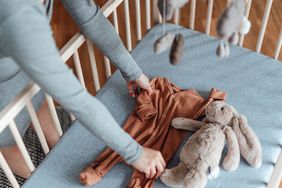 A pregnant woman in a nursery sorting out baby clothes