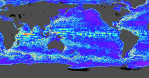 A global map depicting ocean currents with vibrant colors highlighting the flow patterns. The central area shows a band of increased activity, painted in red and yellow tones, against shades of blue and purple in the surrounding regions.