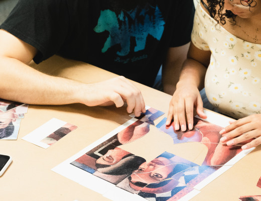 Foto de um homem e uma mulher, do ombro para baixo, jogando quebra-cabeça em uma mesa.