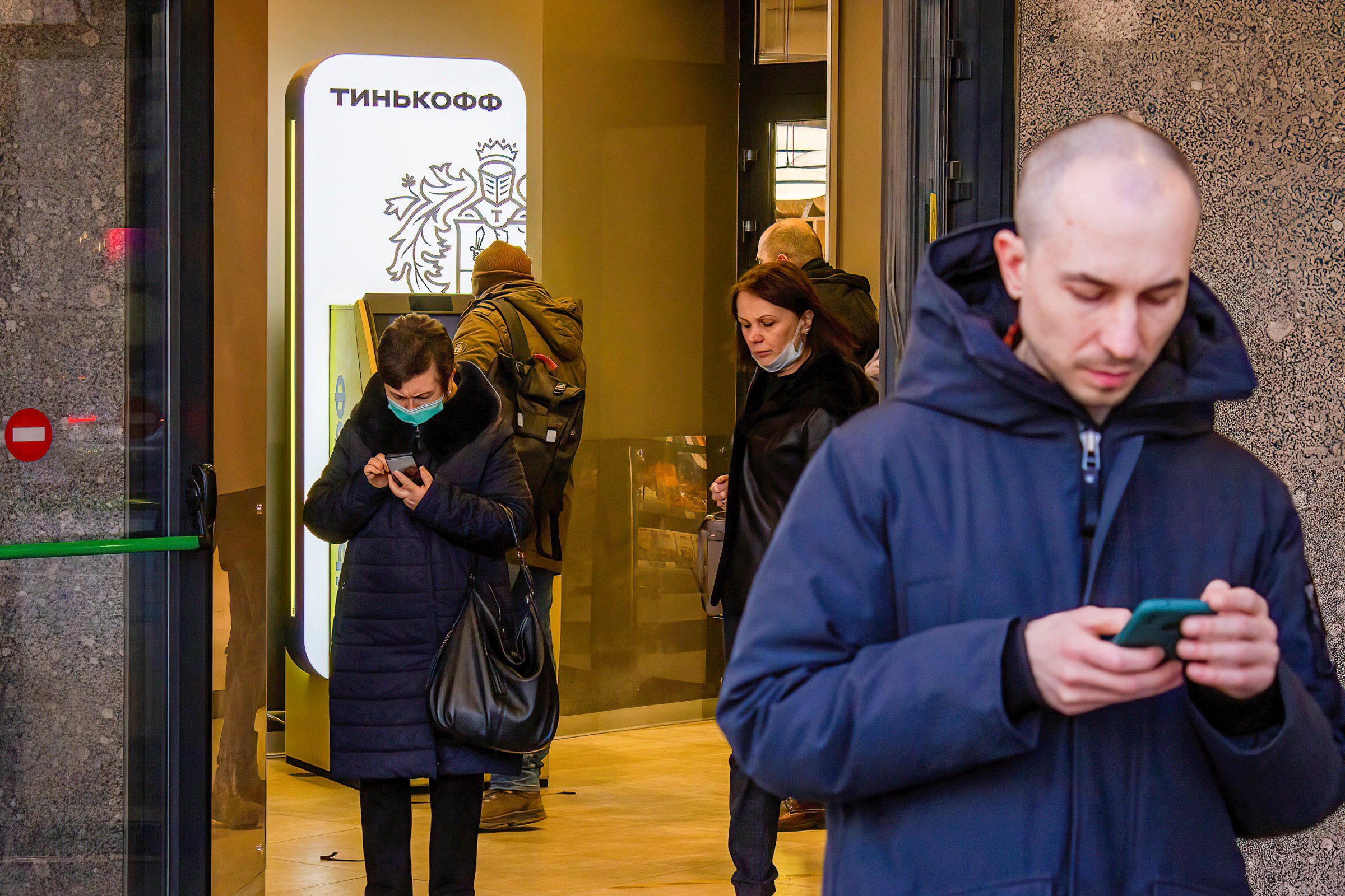 People in Moscow check the Tinkoff app on their phones to find out where they can withdraw US dollars on March 3.