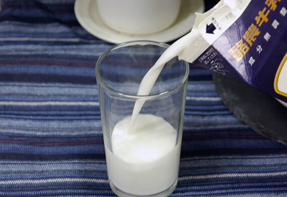 牛乳パック内の牛乳をコップ一杯分減らしている