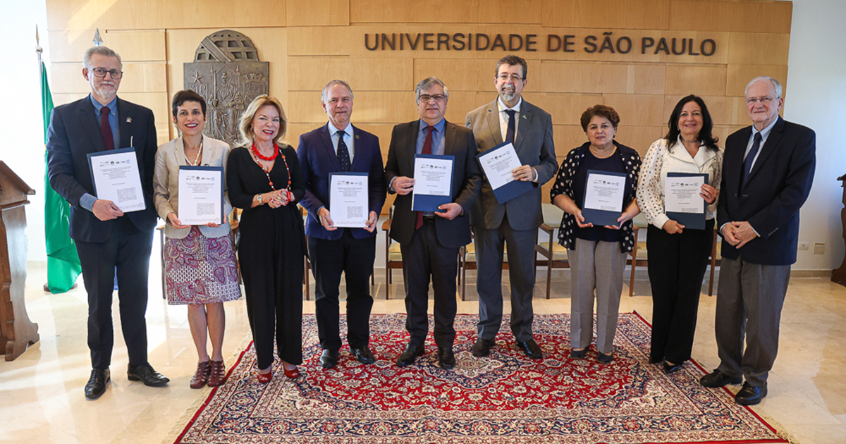 Reitores das universidades estaduais paulistas com certificados em frente à placa da Universidade de São Paulo