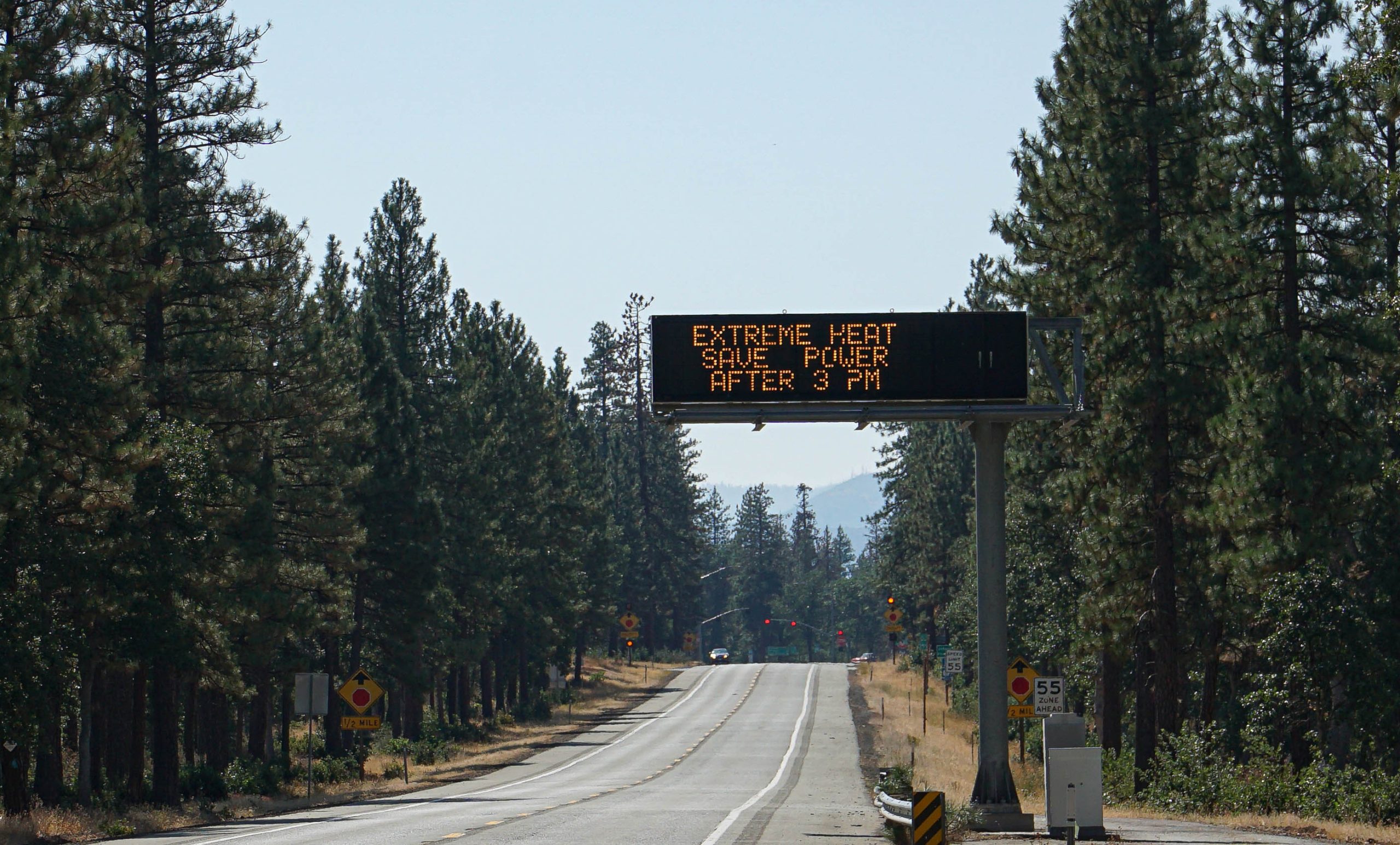 Forest road with electronic heat wave warning sign