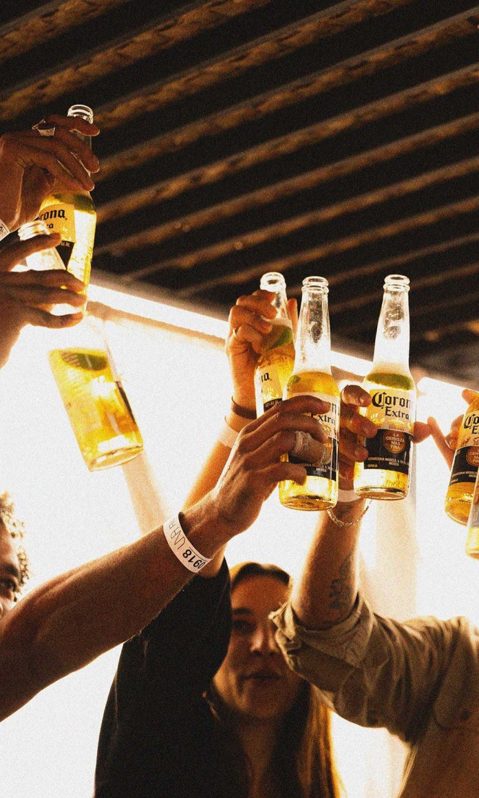 Pessoas brindando com garrafas de cerveja no por do sol