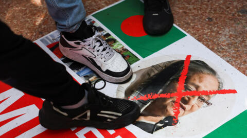 Des manifestants bangladais, à Londres, marchent sur une affiche avec le portrait de la Première ministre démissionnaire, le 5 août 2024.