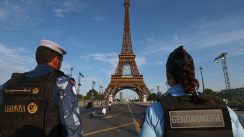 A French policewoman and a Qatari policeman stand guard near the Eiffel Tower as security preparations step up for the Paris Olympics.