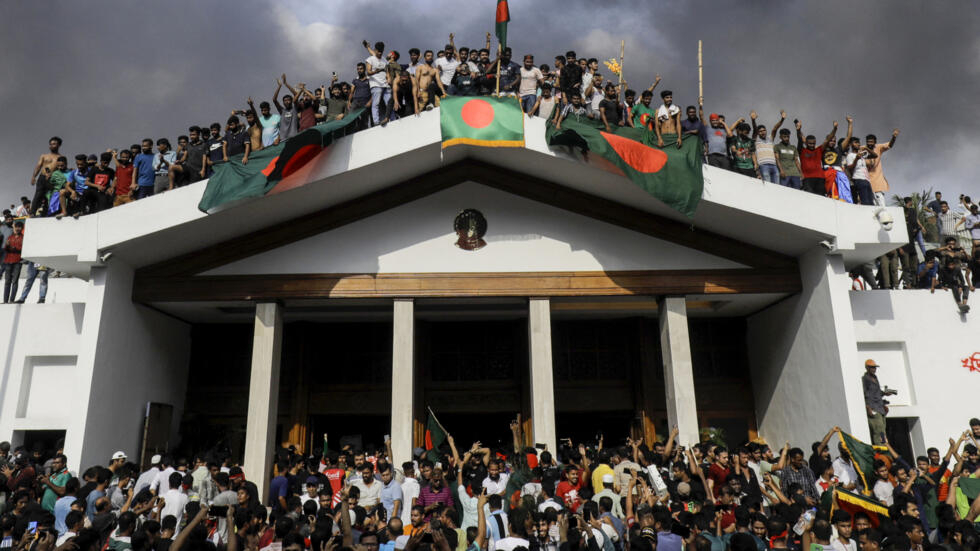 Anti-government protesters display Bangladesh's national flag as they storm Prime Minister Sheikh Hasina's palace in Dhaka on August 5, 2024. 