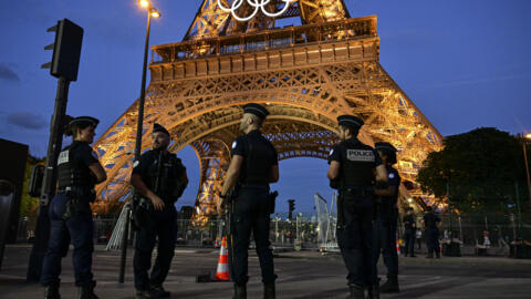 Police officers stand guard near the Eiffel Tower in Paris on July 21, 2024, ahead of the Paris 2024 Olympic and Paralympic Games.