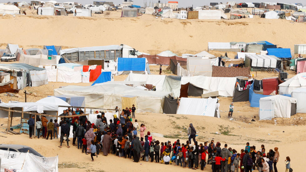 Displaced Palestinians wait to receive free food at a tent camp amid food shortages in Rafah in the southern Gaza Strip, on February 27, 2024. 