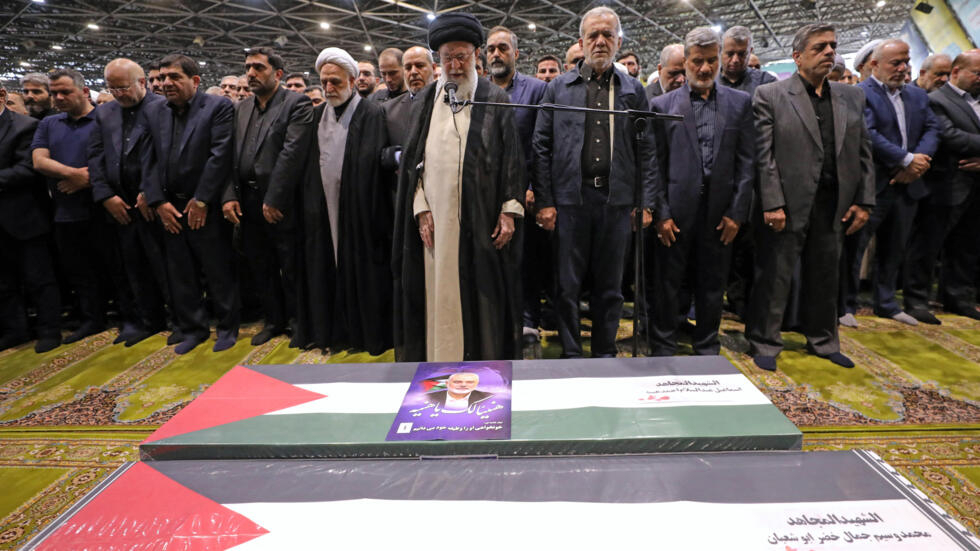 Iranian Supreme Leader Ayatollah Ali Khamenei (C) leads the prayer next to Iranian President Masoud Pezeshkian (C-R), over the coffin of late Hamas leader smail Haniyeh and his bodyguard. 